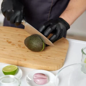 Mietkoch und Diätkoch bereiten eine gesunde Avocado zu”. Der Mietkoch und Diätkoch ist dabei, eine Avocado auf einem Holzbrett zu schneiden